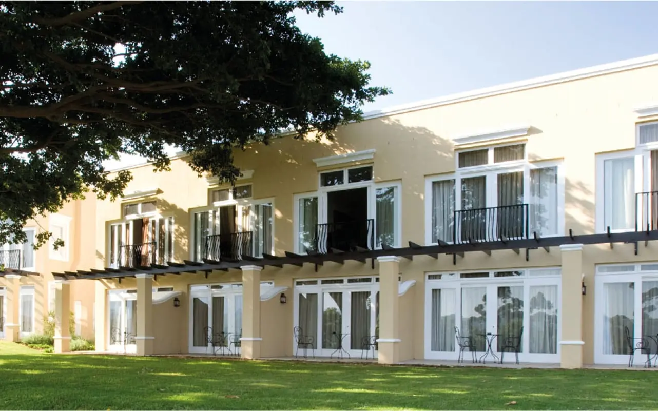 The Devon Valley Hotel's two-storey building behind a lawn and old tree