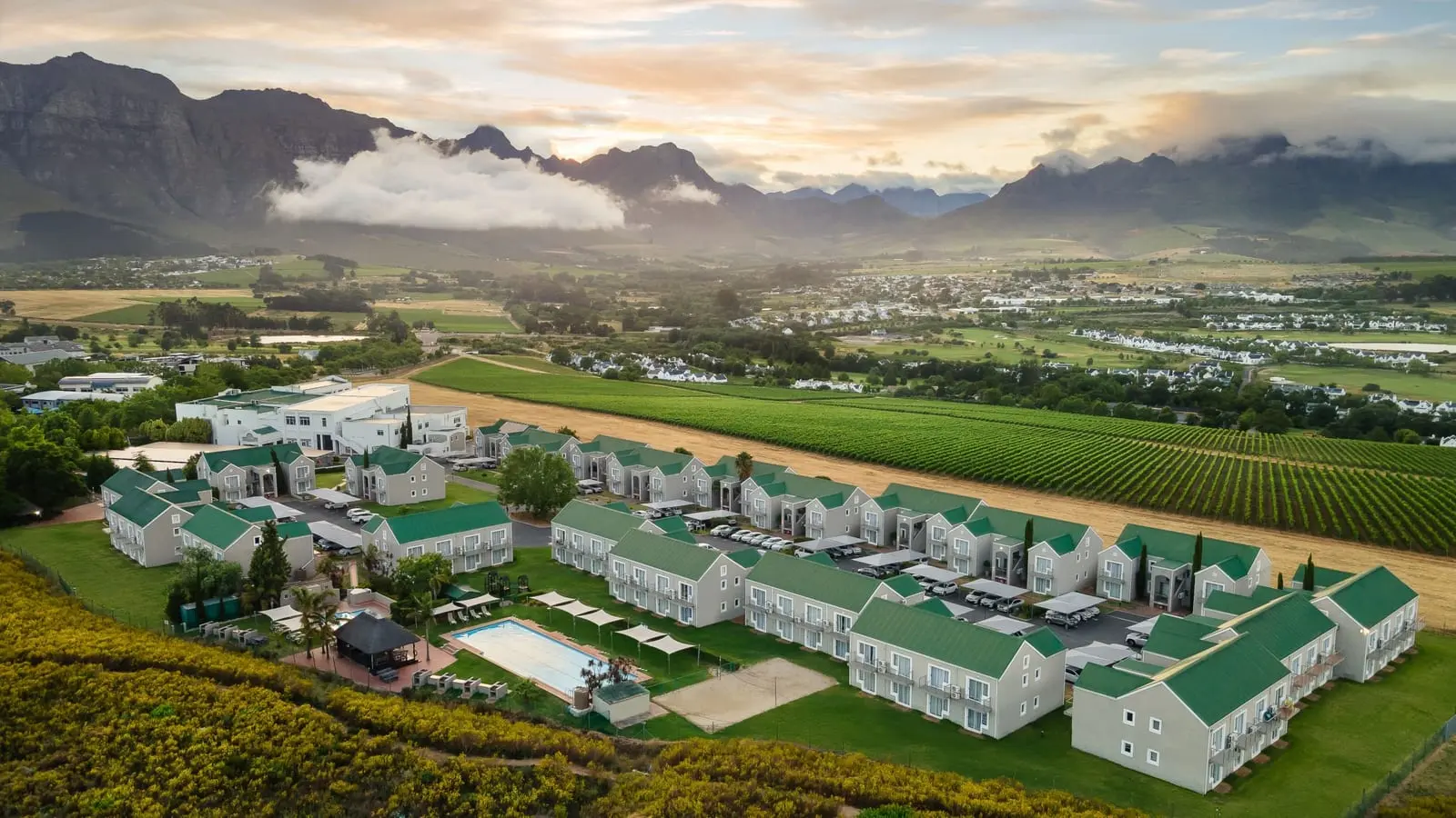 Aerial view of the Protea Hotel Stellenbosch beside vineyards, with mountains behind